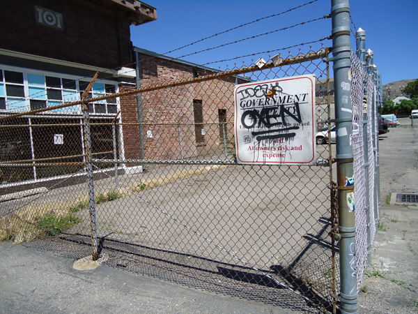 Fence to a government property. OXEN is spray painted on the sign and underlined twice. 